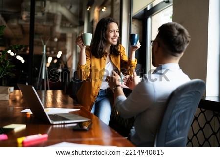 Colleagues laughing in office. Businesswoman and businessman drinking coffee Royalty-Free Stock Photo #2214940815
