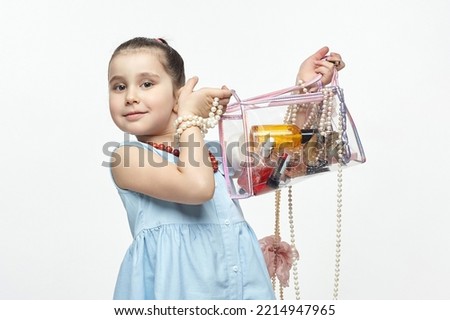 little black-haired fashionista holds a bag of cosmetics in her hands. funny photo shoot of girl in the studio on a white background.