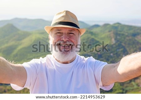 an older man taking a selfie at the top of the mountain