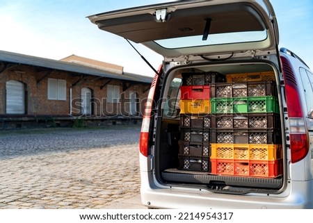 Delivery truck is parked outside near storage on sunny autumn day. Loading and unloading of food products. Christmas pies Christstollen freshly handmade packed in colorful containers in trunk of car