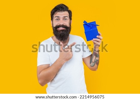 present box for guy in shirt. birthday guy point finger on present box. bearded guy with present box