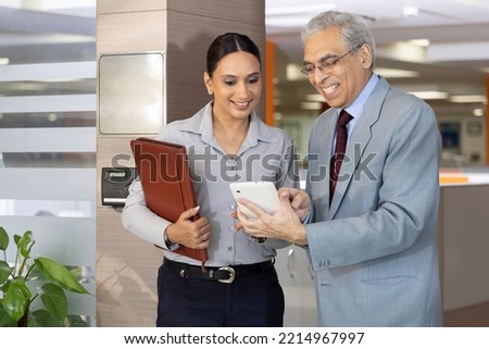 Happy business colleagues in modern office talking and using tablet