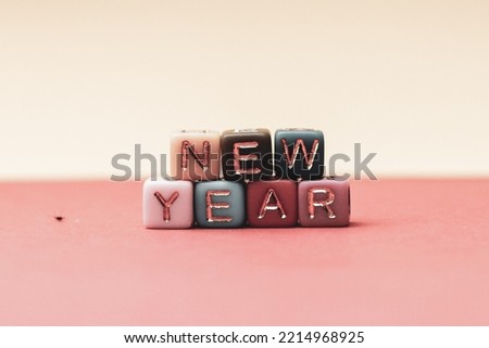 the phrase new year is written in multicolored letters on a pink background. Creative concept for new year greeting card. High quality photo