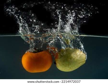 Fruits going into water with splash all around - fresh eating concept.