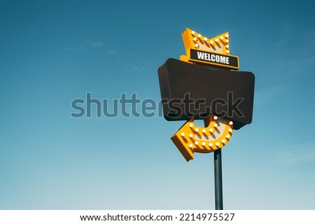 Welcome black copy space frame sign with a yellow arrow with light bulbs. Sky as background. Royalty-Free Stock Photo #2214975527