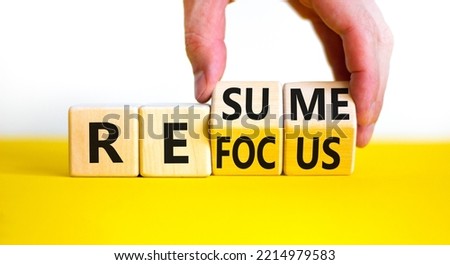 Refocus and resume symbol. Businessman turns cubes and changes the word 'refocus' to 'resume'. Beautiful yellow table, white background. Business refocus and resume concept. Copy space.