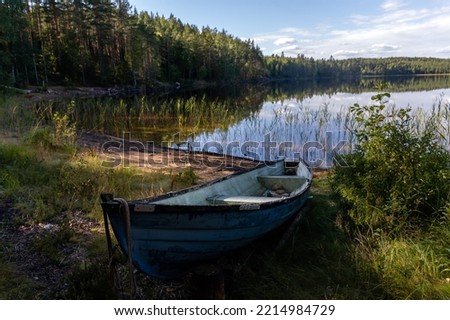 Old blue fiberglass boat on sandy beach in Repovesi National Park, Finland Royalty-Free Stock Photo #2214984729