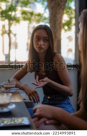Beautiful and attrctive girl friends are hanging out at the cafe while talking about their boyfriends Royalty-Free Stock Photo #2214993891