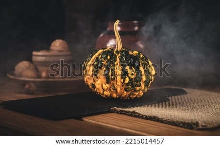 Yellow Pumpkin on wooden table with smoke in the background. Vintage style photo with decorative pumpkin, nuts and pottery. Great for Commercial use and Advertisements.