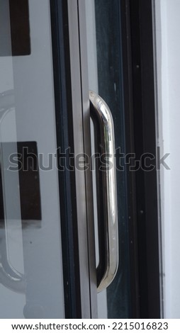 chrome door handle with glass door and black aluminum door frame.
