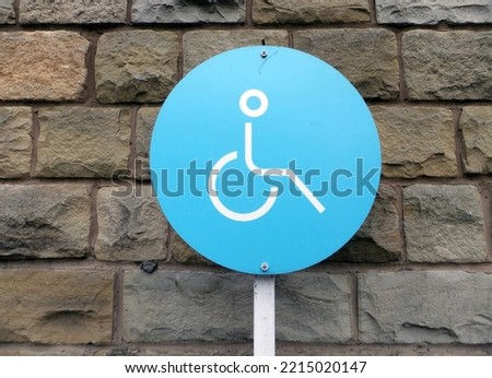 uk standard reserved disability blue metal parking sign against a stone wall