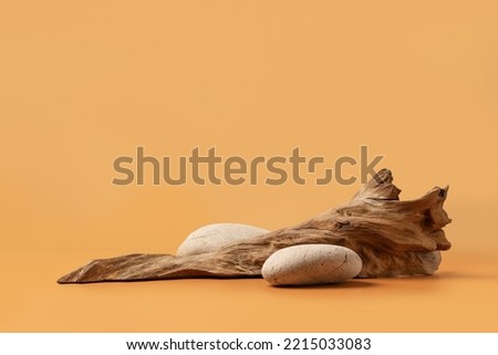 Mockup stage for advertising made with stones and weathered snag on a sandy background with copy space. Natural pedestal for cosmetic product presentation or package advertisement. Royalty-Free Stock Photo #2215033083