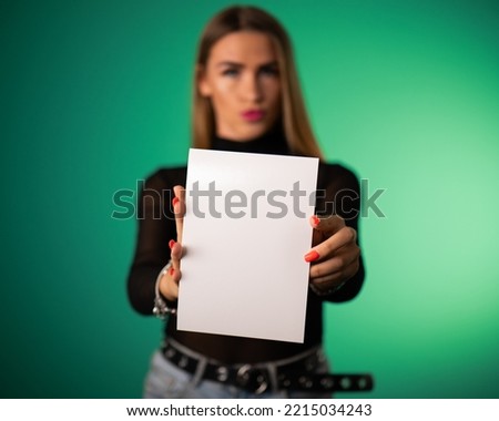 Beautiful young woman model holding an empty blank paper sheet. Perfect for advertising and mockups.