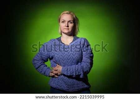 a woman in a blue knitted sweater on a yellow spot of a dark background