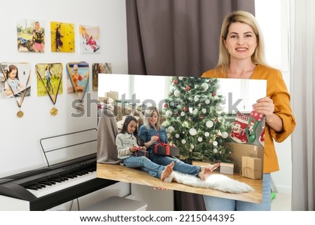 a woman holds a photo of Christmas on a photo canvas.