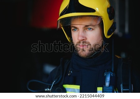 Fireman (firefighter) in action standing near a firetruck. Emergency safety. Protection, rescue from danger