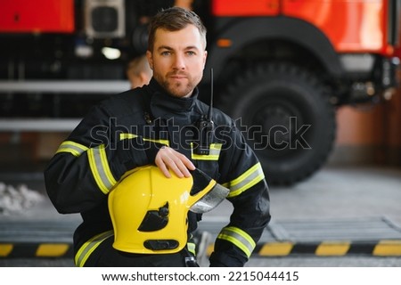 Fireman (firefighter) in action standing near a firetruck. Emergency safety. Protection, rescue from danger