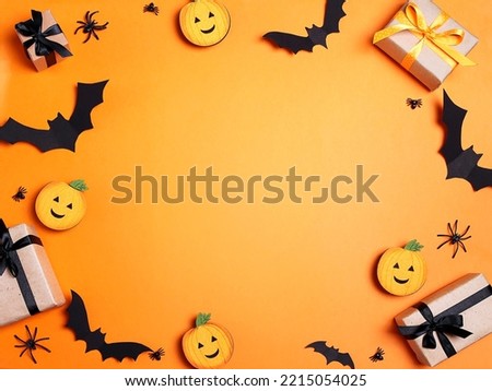 Halloween orange background with gifts, spiders and  bats. Flat lay, top view frame with copy space.