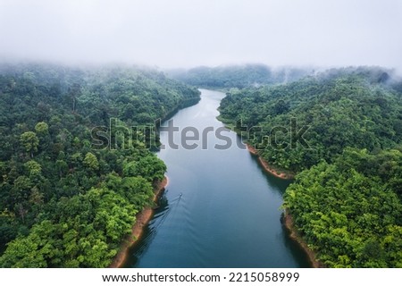 Aerial view of foggy river and boat sailing in tropical rainforest of abundance ecosystem in the morning. Sustainable living and decarbonisation concept Royalty-Free Stock Photo #2215058999
