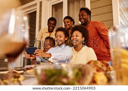 Portrait of happy African American family taking selfie photo at house terrace in evening