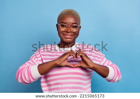 Closeup photo of young girl happy smiling showing love symbol you flirt isolated on blue color background