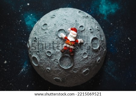 Plasticine Santa Claus lies on the moon against the background of the starry sky. Christmas card.