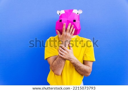 Cool man wearing 3d origami mask with stylish colored clothes - Creative concept for advertising, animal head mask doing funny things on colorful background