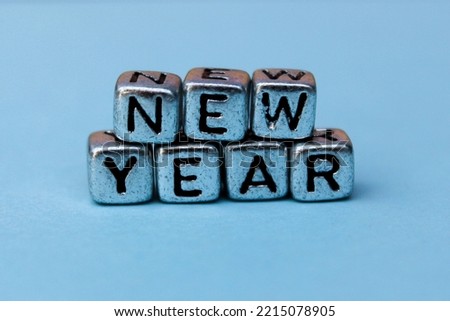 the phrase new year is written in multicolored letters on a blue background. Creative concept for new year greeting card. High quality photo