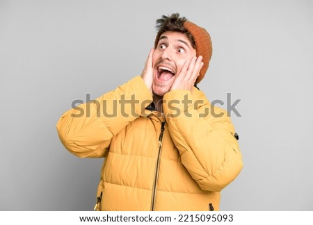 handsome teenager feeling happy, excited and surprised. winter clothes and cold concept