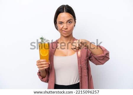 Young hispanic woman holding a cocktail isolated on white background showing thumb down with negative expression