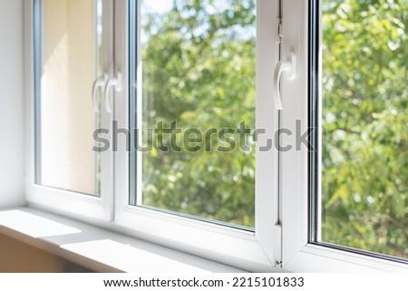 new plastic pvc window with white metal frame installed at modern house, view of blurred green trees. advertising concepts Royalty-Free Stock Photo #2215101833