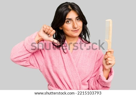 Young woman in a bathrobe holding an hair comb isolated showing a dislike gesture, thumbs down. Disagreement concept.