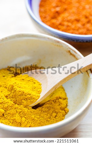 Yellow curry powder in  ceramic bowl on wooden table