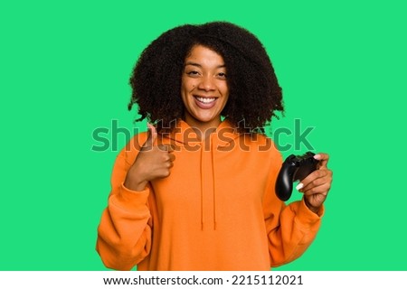 Young African American woman holding a game controller isolated smiling and raising thumb up