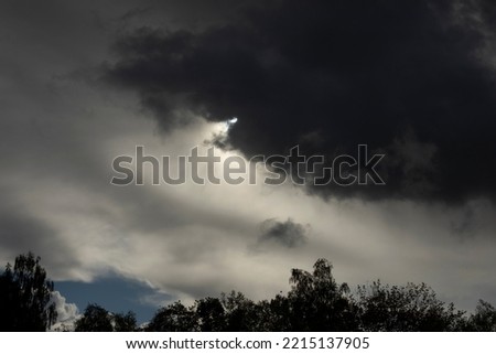Cloud obscures sun. Grey sky. Cloudy weather. Tragic sky over forest.