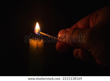 Lighting a candle with match over darkness home Royalty-Free Stock Photo #2215138169