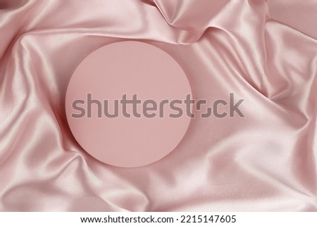 Geometric round platform podium on pale pink silk satin background. Blank minimal cylinder form mock up background for cosmetic product presentation. Top view.