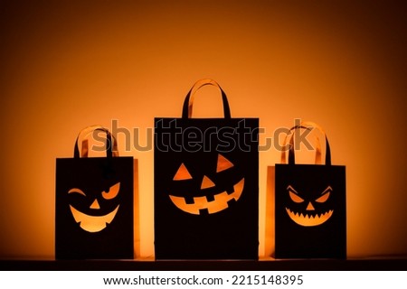 Happy Halloween sale concept background. paper shopping bags with jack pumpkin masks silhouette night illuminated.