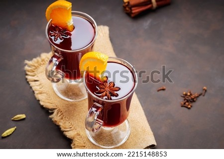 Mulled wine with orange slices and spices on sackcloth. Hot mulled wine and ingredients on a dark background. Warming autumn drink concept