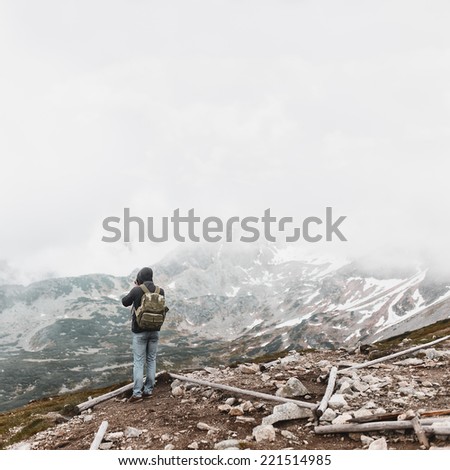 The guy from the back with a backpack in the mountains, take pictures