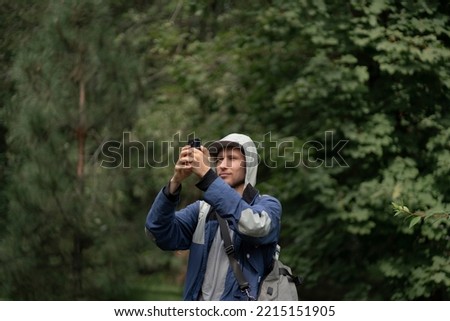 male hiker making photo on a smartphone camera in mountain forest, learning mobile photography