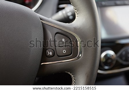 Modern black steering wheel with multifunction buttons for quick control, close-up in the car.
