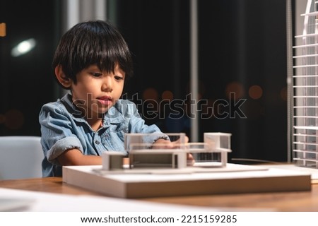 Inspiration kids in occupation in the future, Asian kid playing and concentrating to home model box in the job of parent at office room at night. Skill and learning practice of children's success.