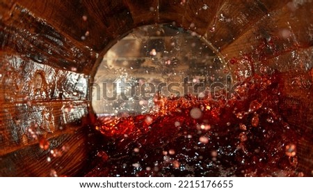 Freeze motion of splashing red wine in wooden barrel. Concept of pouring wine inside a keg. Alcoholic beverage background. Royalty-Free Stock Photo #2215176655