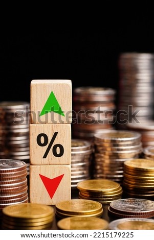 Wooden cube block with icon percentage, symbol arrow up and down on stacks of coins.	                           