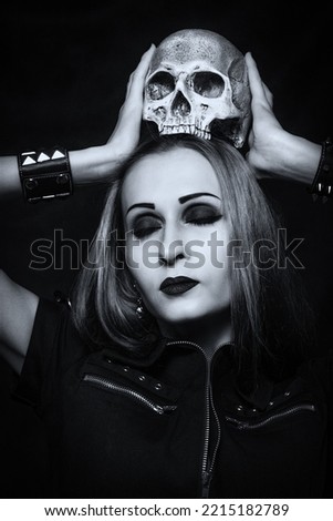 Gothic girl with skull posing over dark background