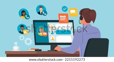 Professional virtual assistant sitting at desk and working with computer: she is talking with customers, replying to messages and planning Royalty-Free Stock Photo #2215192273