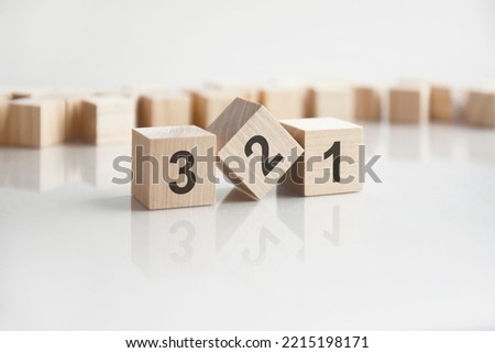 text 321 on wooden blocks with letters on a white background. reflection of the caption on the mirrored surface of the table.