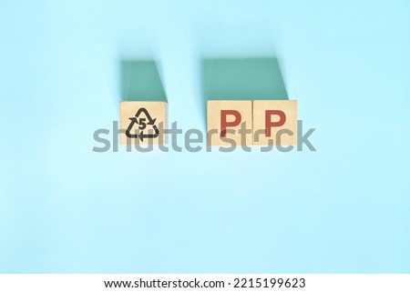 Recycling icon number 5 for PP or polypropylene symbol on wooden blocks flat lay.