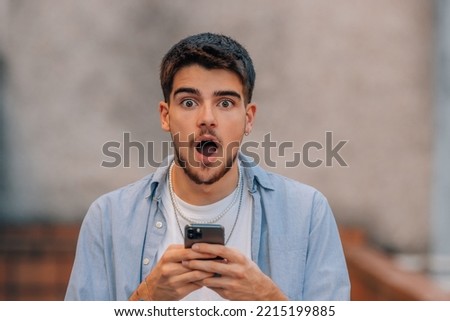 young man in the street with phone and expression of surprise Royalty-Free Stock Photo #2215199885